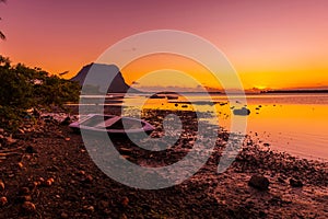 Boats and a low tide ocean at sunset with Le Morn mountain in Mauritius