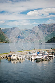 boats moored in calm harbour and majestic mountain landscape Aurlandsfjord Flam