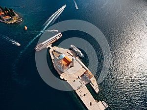 Boats moored near the island of Gospa od Skrpjela on the background of St. George island. Top view