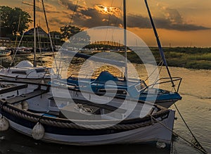 Boats moored on the River Glaven illuminated by the evening glow of the sunset at Blakeney, Norfolk, UK