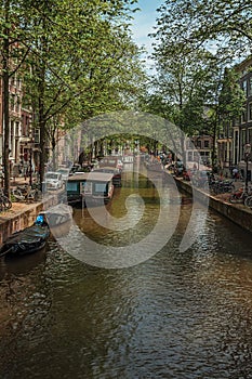 Boats moored at side of canal and brick buildings in Amsterdam