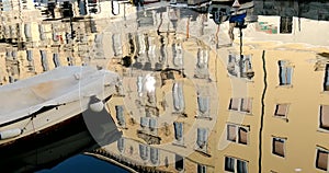 Boats moored on waterway and antique building reflected on water