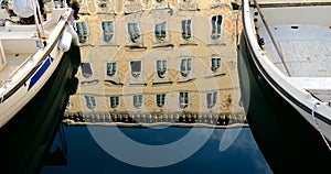 Boats moored on waterway and antique building reflected on water