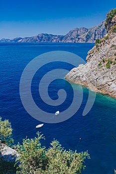 Boats over blue water and coastline near the town of Praiano, along the Amalfi Coast, Italy