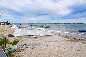 Boats overturned on sand on coastal beach, others in waters