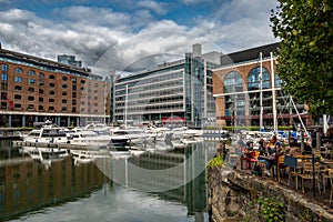 Boats And Ships In St Katharine Docks With Office Buildings And Restaurants In London, UK