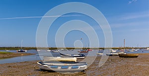 Boats on the shore and moored in Brancaster Bay near Burnham, Norfolk, UK