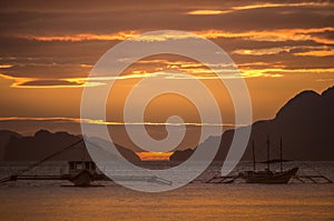 Boats silhouette in the sea on sunset and isles background. Traditional Philippines fishing boat at sunset.