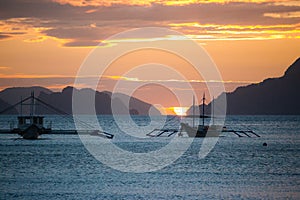 Boats silhouette in the sea on sunset and isles background. Traditional Philippines fishing boat at sunset.