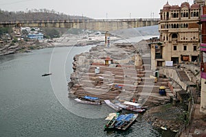 Boats and a small pedestrian bridge on the ghats of narmada river in the holy city of omkareshwar madhya pradesh India