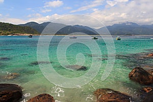 Boats in transparent water of beach Aventueiro of island Ilha Grande, Brazil