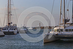 Boats in Vlichada harbor on Santorini island in Greece in the morning at sunrise. The background is a blue sky with white clouds