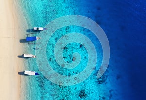 Boats on the water surface from top view. Turquoise water background from top view. Summer seascape from air. Gili Meno island, In photo