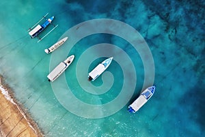 Boats on the water surface from top view. Turquoise water background from top view. Summer seascape from air. Gili Meno island, In