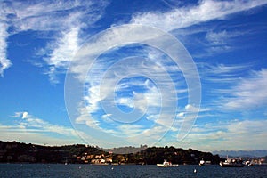 Boats and yacht in front of the Ligurian coast under a cloudy sky view from the boat