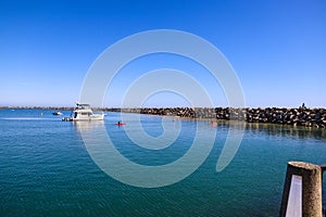 Boats and yachts docked in the deep blue ocean water of the Dana Point Harbor with people and colorful paddle boards