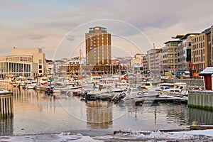 Boats and yachts docked in a harbor with the city in the background in Bodo, Norway. Sea vessels at a port in the ocean