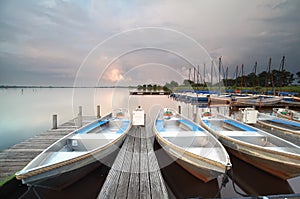 Boats and yachts by pier during showery sunset