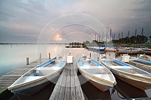 Boats and yachts by pier during showery sunset photo