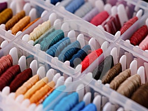 Bobbins with different colour embroidery threads in a plastic sorting box.