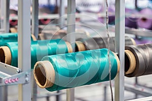 bobbins with threads of different colors on the machine of a clothing factory
