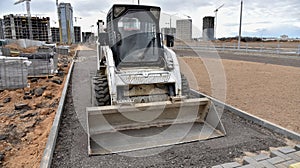 Bobcat skid-steer loader for loading and unloading works on city streets. ompact construction equipment for work in limited