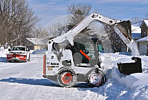 Bobcat skid steer removing snow from driveway