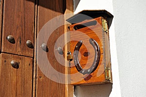 Buzon de cartas de madera con candado y herradura en la fachada de una vivienda unifamiliar