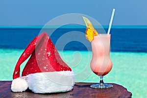 Bocal of drink is on a beach table with Santa hat photo
