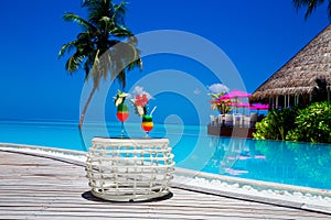 Bocal of fruity cocktail on a beach table. Maldives Island landscape. Tropical fresh juices on white sandy beach. Colorful fruity