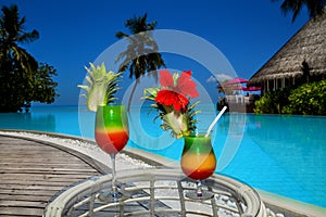 Bocal of fruity cocktail on a beach table. Maldives Island landscape. Tropical fresh juices on white sandy beach. Colorful fruity