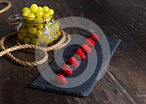 Bodegon fruit, fresh strawberries on slate plate with glass jar with fresh grapes on aged basis photo