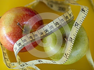 Bodegon mounted on a yellow background and composed of two apples and a tape to measure the waist photo