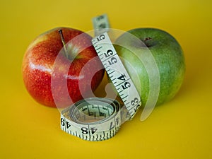 Bodegon mounted on a yellow background and composed of two apples and a tape to measure the waist photo