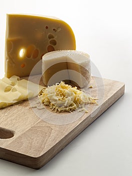 Photographic still life with sheep cheeses and to melt with slices and scratches of it on a cutting board photo