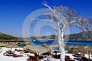 Bodrum, Turkey - August 2020: Lujo`s snow white beach with baboon umbrellas, wooden sunbeds, emerald colored Aegean Sea photo