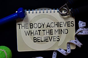 The Body Achieves What The Mind Believes write on a book isolated on black background. Workout concept photo