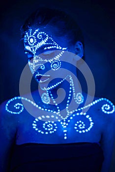 Body art on the body and hand of a girl glowing in the ultraviolet light