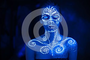 Body art on the body and hand of a girl glowing in the ultraviolet light