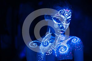 Body art on the body and hand of a girl glowing in the ultraviolet light