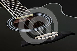Body of black electric acoustic guitar on dark background