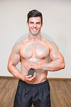 Body builder holding bottle with supplements in gym