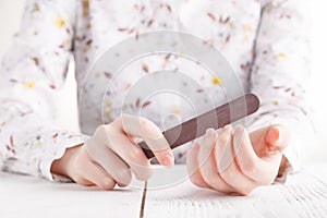 Body-care of hands. Woman polishing fingernails with the nail file