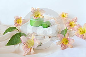 Body care products, white bath towel with pink daylily flowers, side view - the concept of gentle morning body care