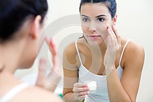 Body care. Woman applying cream on face photo