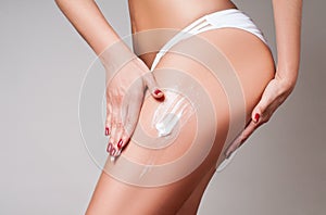 Body care. Woman applying cream on legs and buttocks from cellulite