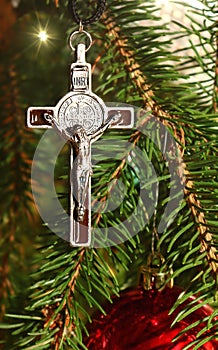 Body of Christ on real evergreen tree decorated with red bulbs