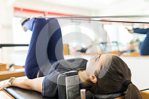 Body Conscious Woman Exercising On Pilates Reformer Machine photo