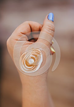 Body cream on the girl's hand with blue fingernail