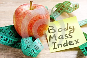 Body Mass Index BMI written on a memo stick and apple.